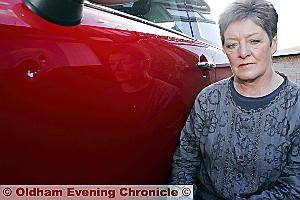 ANGRY Mrs Jackson and the £600 dent, circled, in her car after coming under attack from brick-throwing louts 
