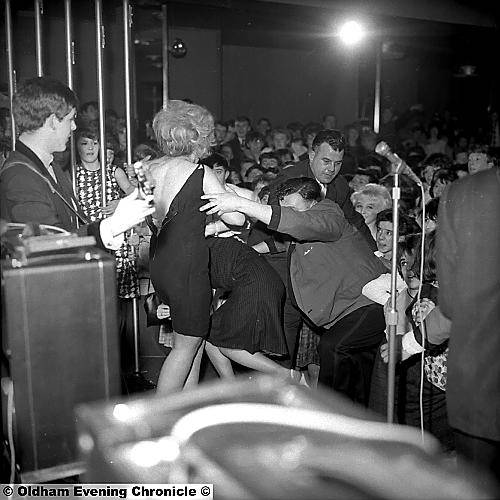 HELP! . . . this woman almost lost her dress which ripped as fans climbed over each other to reach their idols (that's Paul McCartney, left) and bouncers pulled them back into the audience 
