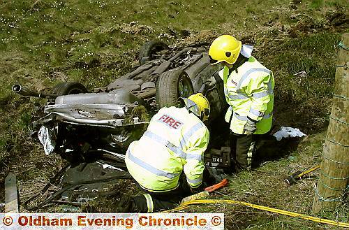 WRITE-OFF . . . firefighters examine the wrecked car 
