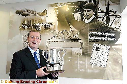 SOARING success . . . Steve Kilroy with the prestigious 504 Trophy, next to a photo of aircraft pioneer AV Roe 