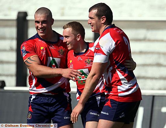 WELL DONE, MATE: David Cookson (left) and Rob Foxen congratulate scorer Chris Murphy, who bagged Oldham’s seventh try. 