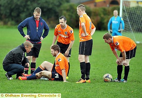WHERE DOES IT HURT? . . . Liam Jackson, of Oldham GPO, grimaces as he is attended to by one of his club officials.