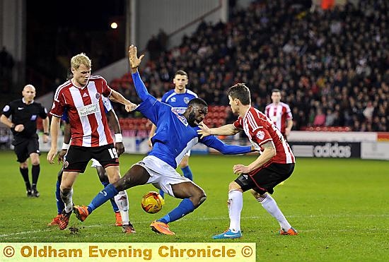 Jabo Ibehre falls to ground under the challenge of two defenders.