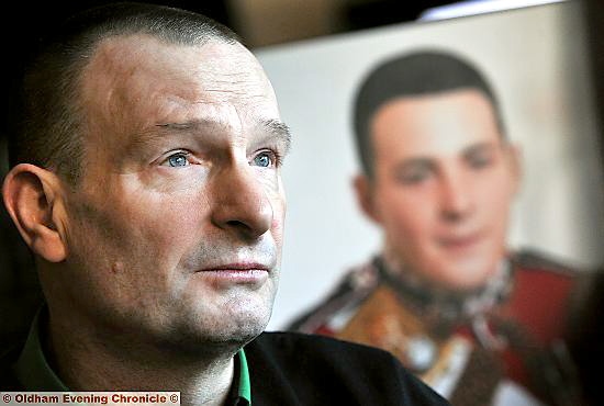 Murdered soldier Lee Rigby's father Phil McClure, with his late son’s picture in the background 
