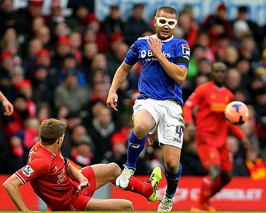 man behind the mask: James Wesolowski hurdles a challenge from Liverpool and England captain Steven Gerrard. 
