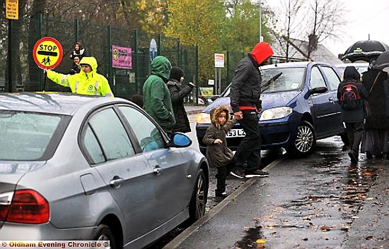 Children and parents are forced to cross the road between parked cars outside Bare Trees Primary School, Chadderton. 