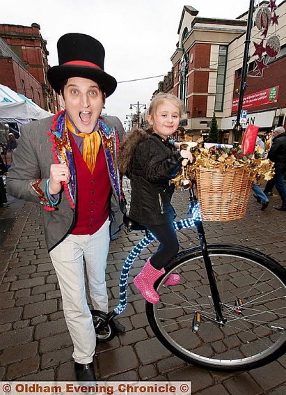 THAT’S magic! Festive Foxley, performed tricks for the shoppers and Madison Taylor, aged six, gets a lift on his bike
