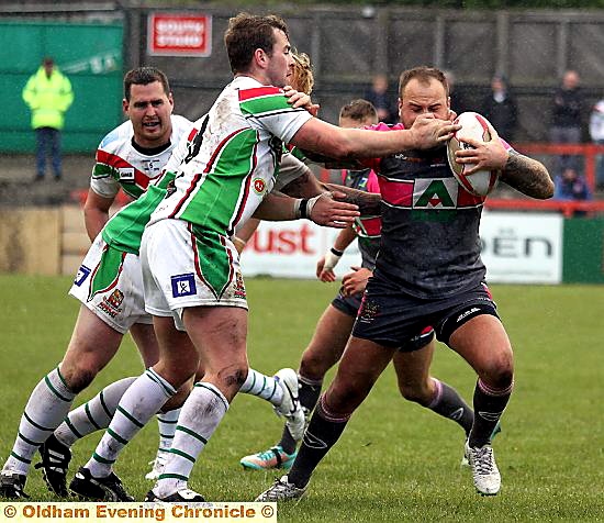 OLDHAM’S Steve Roper takes a blow to the face as he tries to burst through the Keighley Cougars line of defence. 
