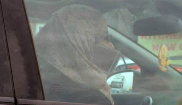 Woman driver on mobile phone attached to scarf.