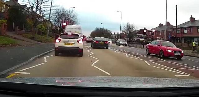 WITH the lights clearly on red,  and other vehicles stopped, the driver approaches the crossing
