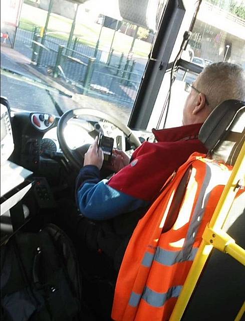 CAUGHT on camera . . . the bus driver uses his phone at the wheel