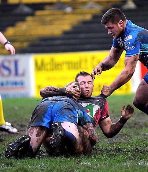 FLOORED . . . Oldham’s Adam Clay (left) is hauled to the ground by two Barrow tacklers.
