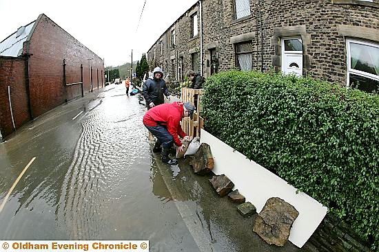 STEM the tide: residents battle against the elements in Delph New Road, Delph, as the floods threaten to take hold