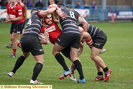 IT TAKES THREE . . . to stop Oldham’s Jack Spencer, who is halted in his tracks by the Broncos.