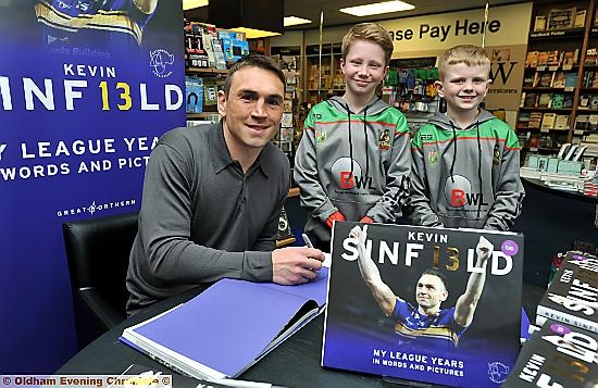 STAR SIGNING: Kevin Sinfield pens a message in his new book at Waterstones in Spindles, flanked by young fans Peter White and Buckley Kershaw, both of whom play for the ex-Leeds Rhinos star’s former amateur club Waterhead at under-10s level.