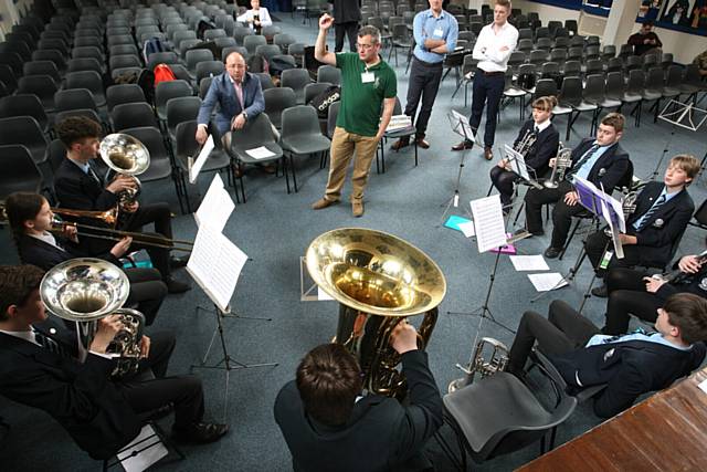 Musician Gavin Green (green top), from the Brigade of Guards, instructs the Saddleworth School Brass Xplosion band.