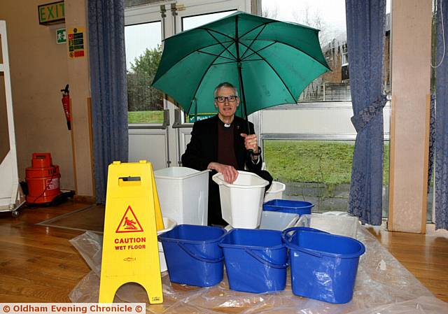 APPEAL . . . Father Tony Mills, of Church of the Holy Family, with buckets full of rain water in the hall

