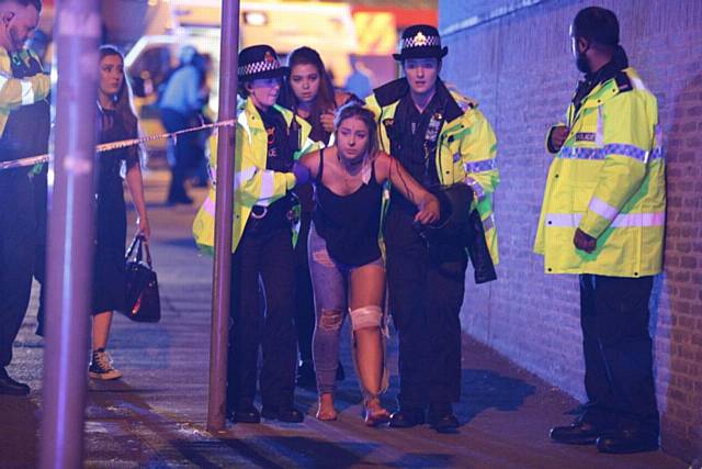 An injured girl is led away by police to a waiting ambulance after the concert explosion 