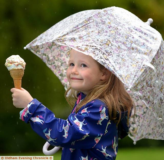 KEEPING dry . . . Six-year-old Lili Fletcher enjoys ice cream and rain