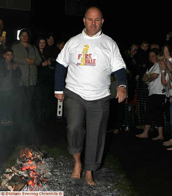 FIRE walker . . . Terry Flanagan, chairman of Mahdlo, Oldham, walks over hot coals for charity