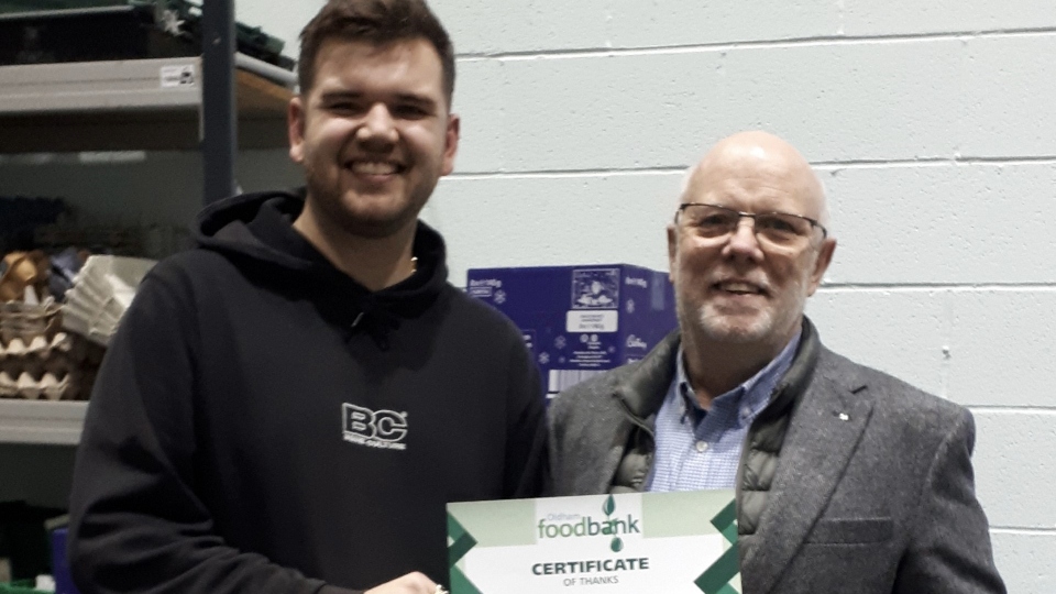 Jon Stocker presents the Aldi vouchers to Tom Lewis-Hood from the Oldham Foodbank