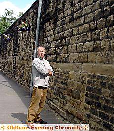 MISSING . . . Councillor Keith Begley with the remaining baskets and the bare wall 
