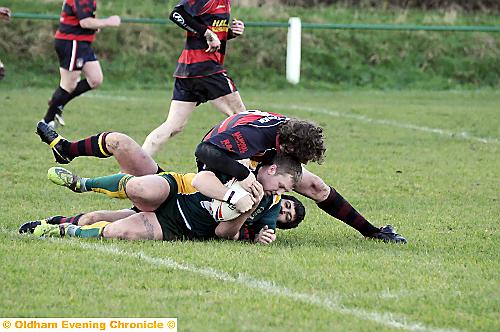 OVER YOU GO . . . Darren Fletcher of St Anne’s is wrestled to the ground by Ovenden's Gareth English and Mat Collins. 