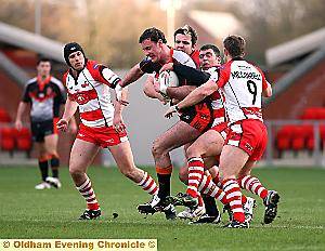 CHARGING THROUGH: Robert Roberts (centre) powers on through the tackles for Oldham.