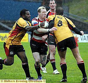 ACTION MAN . . . Paul Reilly tries to squeeze through a pair of Hunslet tackles in the driving rain at Boundary Park 