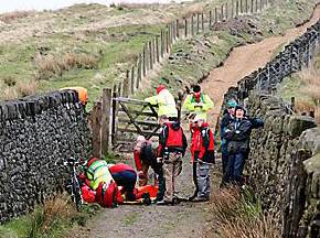 PRAISED . . . Alan Gerrard (green cap, right) and Brian Billington (extreme right) look on as medical teams work on the injured man 
