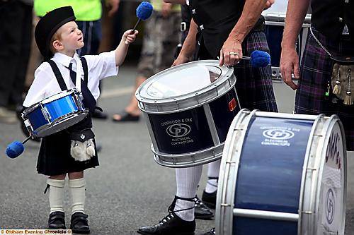 IT’S TOO HEAVY . . . A tiny member of the Oldham Scottish Pipe Band takes a break 