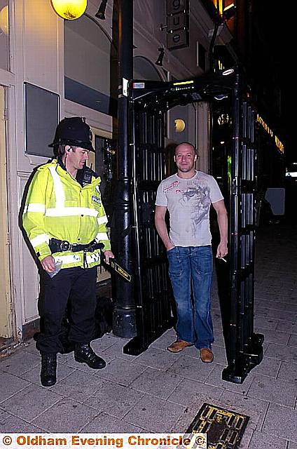 Operation in Oldham town centre involving police, Trading Standards and licensing officers. The police construct a 'knife arch' metal detector. Pic shows PC Pickles and Jason Dalton outside Vogue.