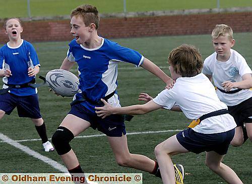 DANE Taylor (centre) of Hodge Clough Juniors ‘A’ escapes the challenge of a Friezland player during the Oldham Schools’ Year Six tag rugby competition.