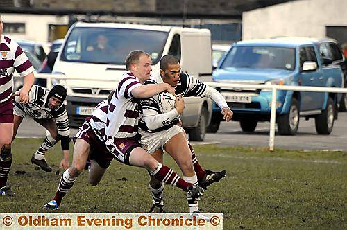 Saddleworth’s Danny Adams is grabbed by Millom’s Paul Carter. 