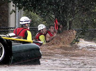 RESCUE struggle . . . workers save a man clinging to a tree in Toowoomba. 