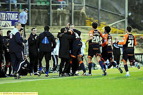 let’s dig it in the dug-out . . . Oumare Tounkara gets a hug from manager Paul Dickov and Lee Duxbury after scoring Athletic’s second goal against Plymouth. 