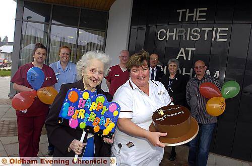 PARTY time . . . Julie Davies, superintendent radiographer, holds the celebration cake, while Oldham fund-raiser Lillian Walsh waves the happy birthday sign, to mark the first year along with fund-raisers and staff 