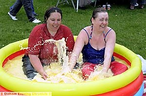 LONG to rain over us — in custard . . . Natalie Hughes (left) and Stacey Dennis braved a sponsored custard bath to raise money for the Scott Ward Schofield Fund and Crazy Cats charities during the Jubilee celebrations at Limeside Park 
