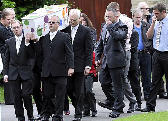 HEARTBREAK . . . Jamie’s father Kenny (right) holds a tissue to his face as the coffin is carried into church 