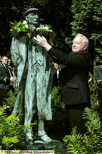LOCAL hero: parish council chairman Brian Lord places a garland of white roses on the statue of poet Ammon Wrigley LOCAL hero: parish council chairman Brian Lord places a garland of white roses on the statue of poet Ammon Wrigley