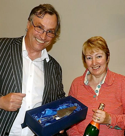 Simon Cooke of VAO presents winner Gillian Froggatt with a bottle of bubbly and an engraved cake slice, donated by Jackson’s of Tommyfield Market  

