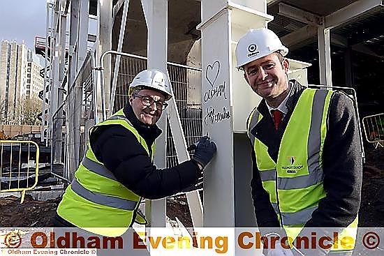 KEY milestone...Jim McMahon and Anthony Dillon sign the final steel beam on the new sports centre.