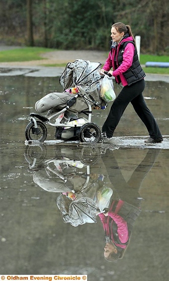 STRUGGLE . . . mum Alison Brennan pushes pram through standing water 

