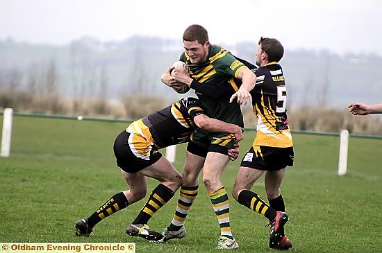 STUCK IN THE MIDDLE: Oldham St Anne’s captain Chris Carter is held by two Elland rivals 