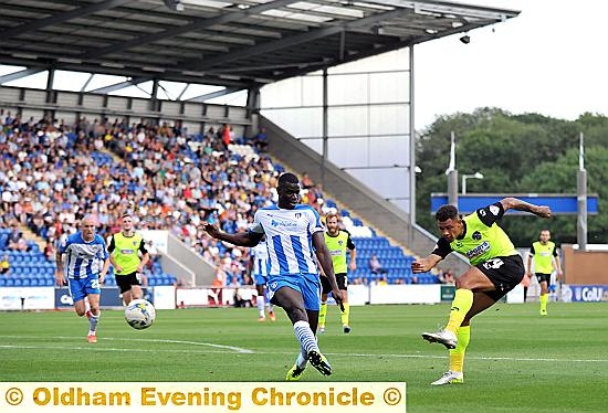 Athletic’s powerful striker Jonson Clarke-Harris unleashes a shot at goal, but his speculative effort fails to find the target.