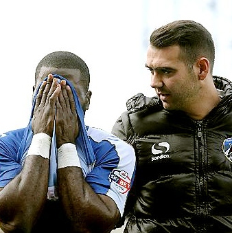 PAIN GAME: George Elokobi is helped off the pitch by Athletic physio Jon Guy. 