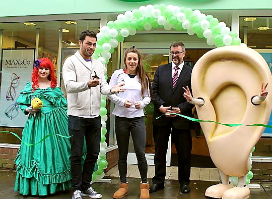 St Helens Super League player Mark Flanagan cuts the tape, assisted by swimmer Jessica Fullalove and store director Nigel Williams.