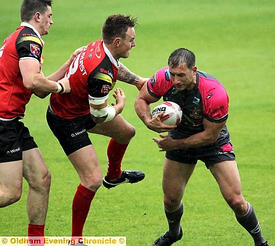 BEST FOOT FORWARD: Oldham’s Adam Neal confronts two Crusaders defenders.