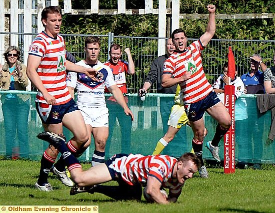 OVER WE GO . . . players and fans celebrate as Richard Lepori dives in for Oldham’s first try against Swinton Lions. PICTURE by TIM BRADLEY