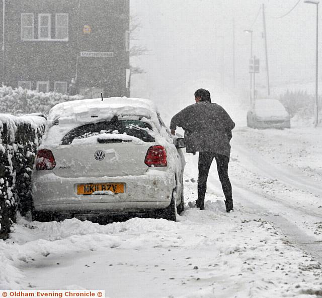 A DRIVER clears her car of snow on Doctor Lane, Scouthead